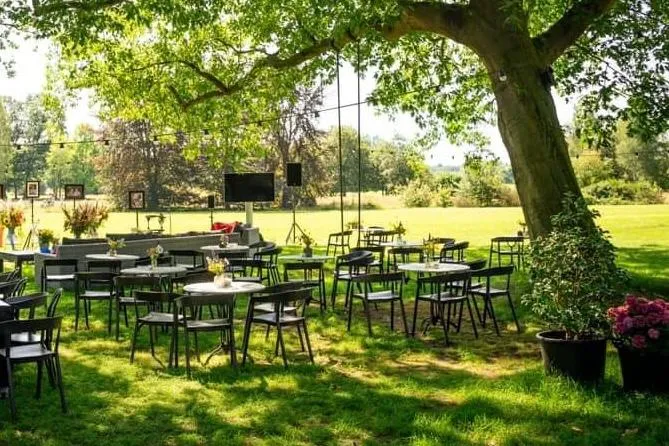 Buitenlocatie met tafels onder de bomen