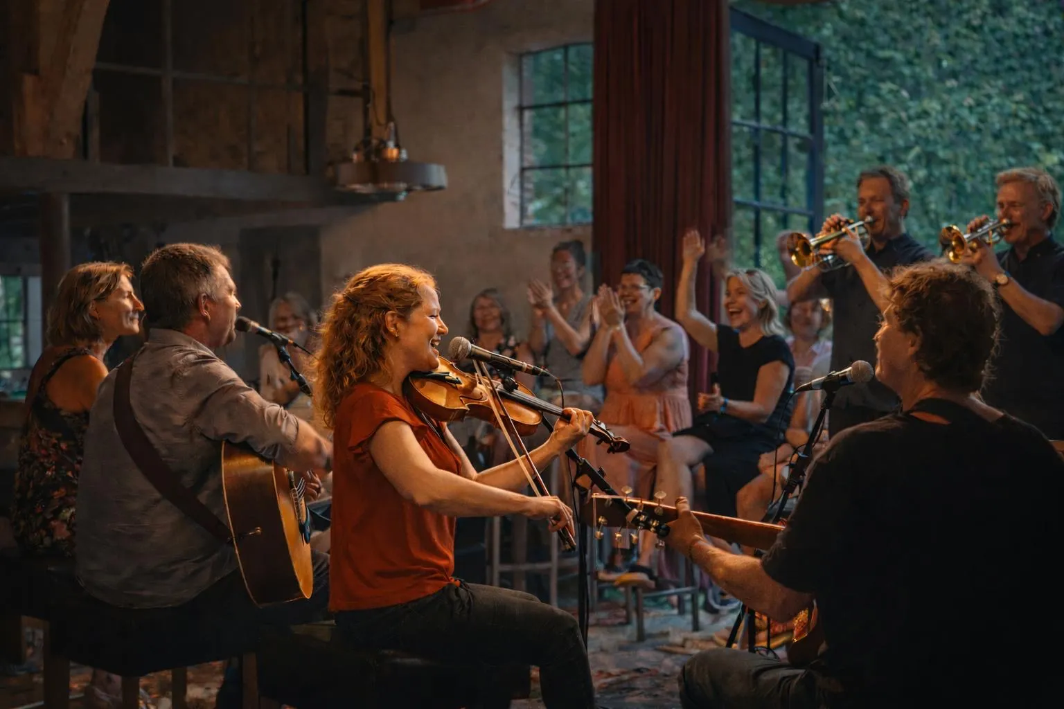 Muzikanten en publiek genieten samen tijdens een intiem optreden in een sfeervolle schuur
